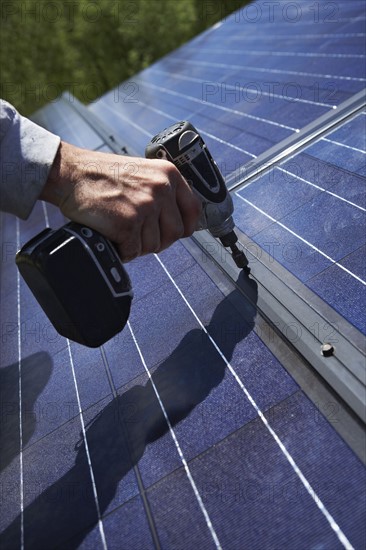 Construction worker installing solar panel on roof. Photo : Shawn O'Connor