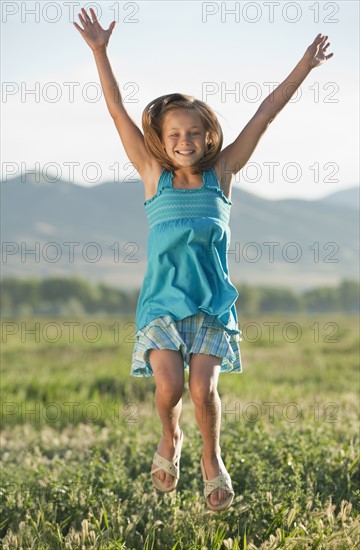 Young girl jumping in field. Photo : Mike Kemp