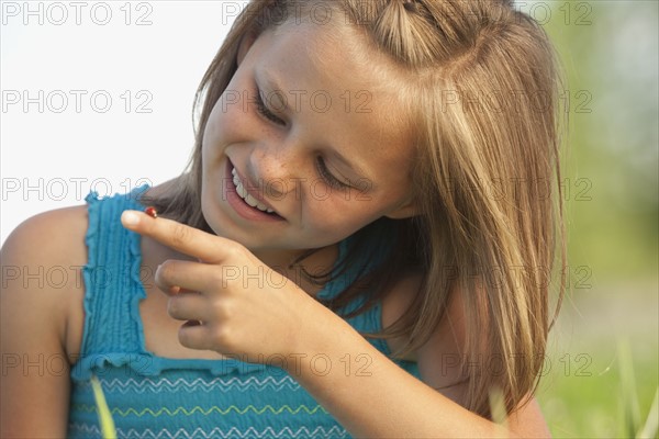 Young girl looking at a ladybug. Photo. Mike Kemp