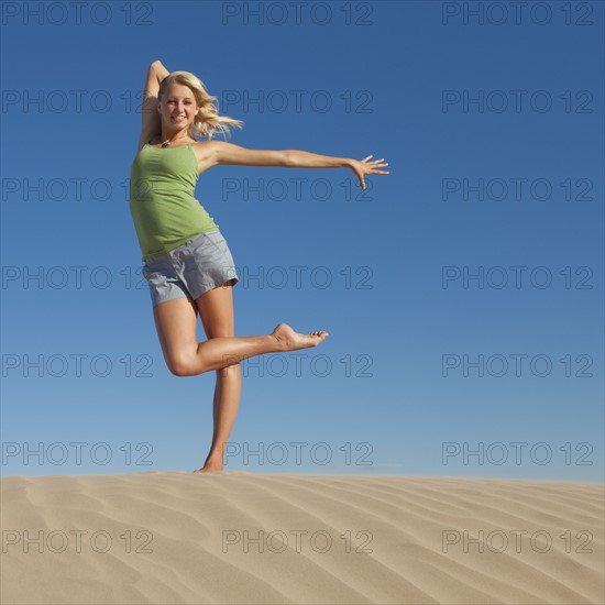 Woman doing dance pose at the beach. Photo : Mike Kemp