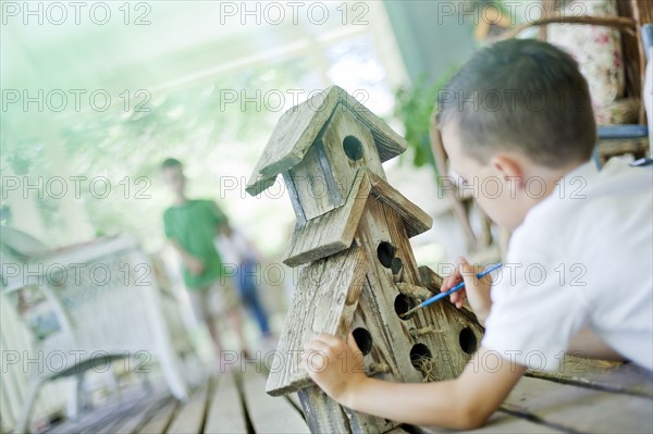 Young boy painting a birdhouse. Photo : Tim Pannell