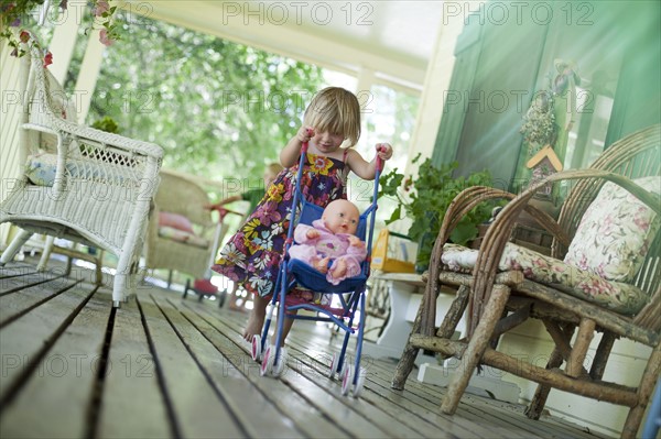 Little girl pushing doll in stroller. Photo. Tim Pannell