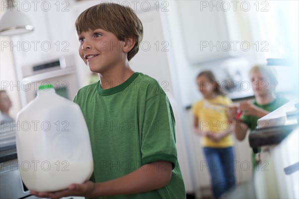 Young boy carrying jug of milk. Photo : Tim Pannell