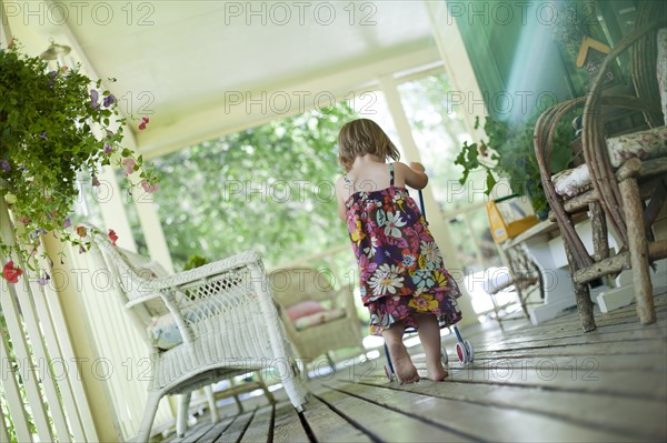 Little girl pushing stroller on porch. Photo : Tim Pannell