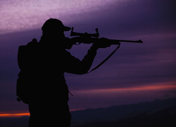 Hunter looking through scope of rifle. Photo. Mike Kemp