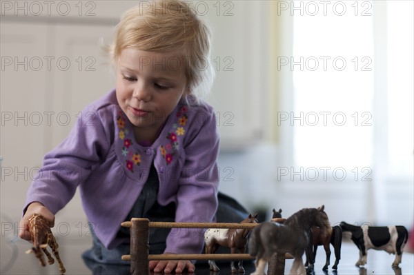 Young girl playing with toy animals. Photo. Tim Pannell