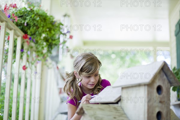 Young girl painting a birdhouse. Photo : Tim Pannell