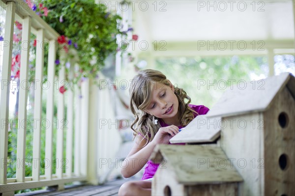 Young girl painting a birdhouse. Photo : Tim Pannell