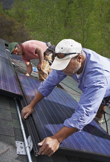 Construction workers installing solar panels on roof. Photo. Shawn O'Connor