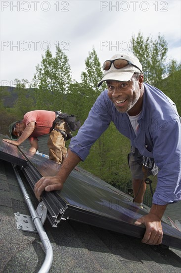 Construction workers installing solar panels on roof. Photo : Shawn O'Connor