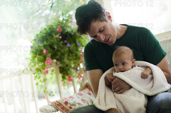 Father sitting on porch with his baby daughter. Photo : Tim Pannell