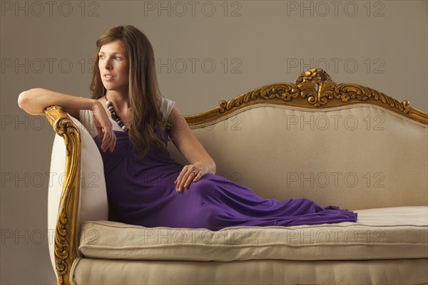 Elegant woman lounging on antique sofa. Photo. Mike Kemp