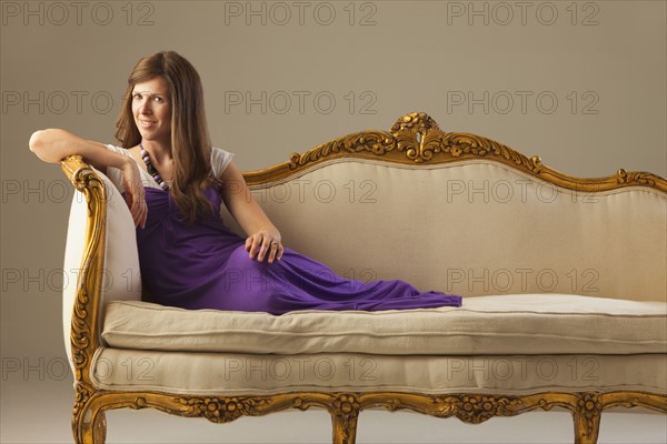 Elegant woman lounging on antique sofa. Photo : Mike Kemp