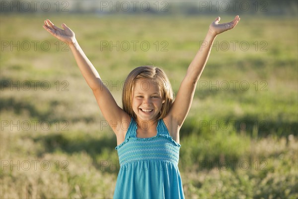 Young girl standing in field with her arms raised. Photo : Mike Kemp