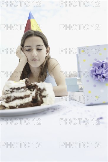 Young girl staring at birthday cake. Photo : momentimages