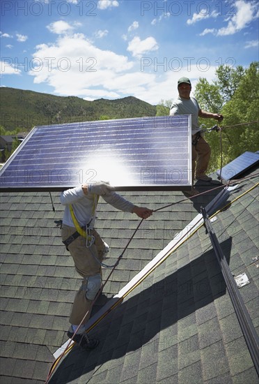 Construction workers installing solar panels on roof. Photo : Shawn O'Connor