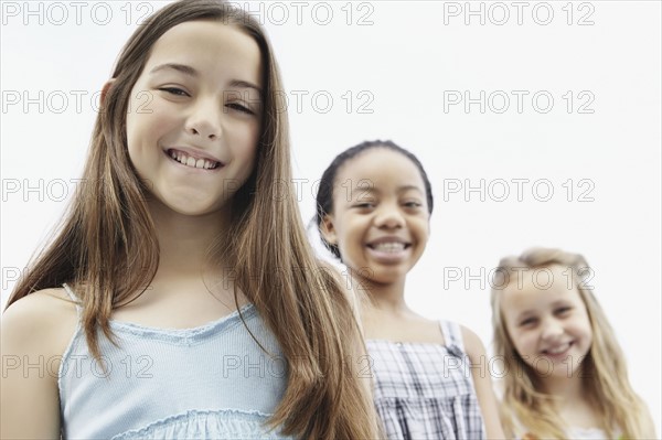 Three girls standing in a row. Photo. momentimages