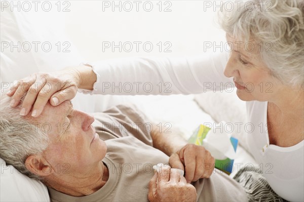 Senior woman caring for man with a fever. Photo. momentimages