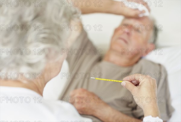 Senior woman caring for man with a fever. Photo. momentimages