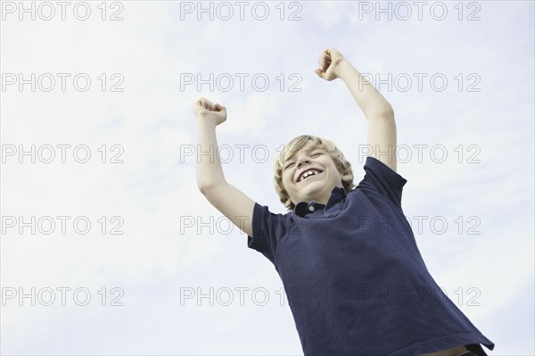 Happy young boy raising his arms in the air. Photo. momentimages