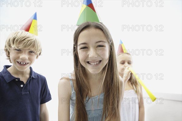 Three children wearing birthday hats. Photo. momentimages