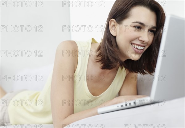 Smiling brunette woman browsing the internet. Photo. momentimages