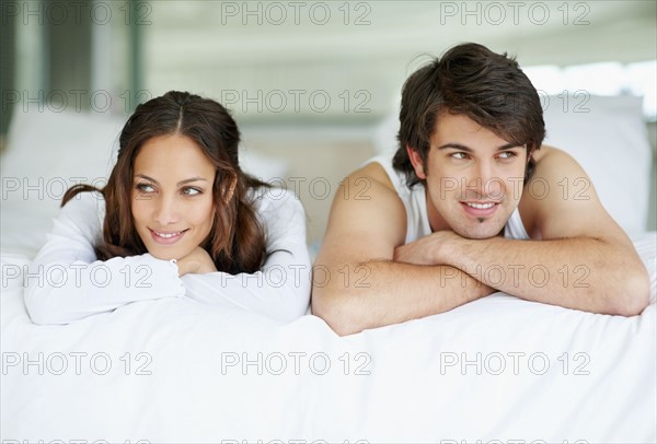 Daydreaming couple lying on bed. Photo. momentimages