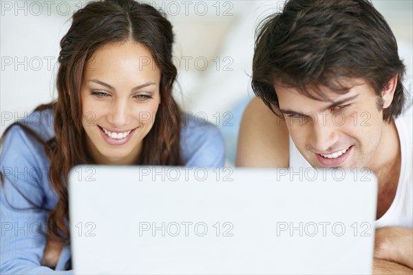 Couple looking at laptop together. Photo. momentimages