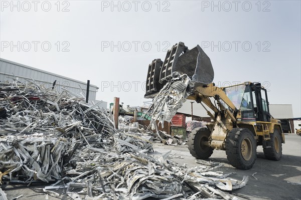 Backhoe dumping recyclable metal.