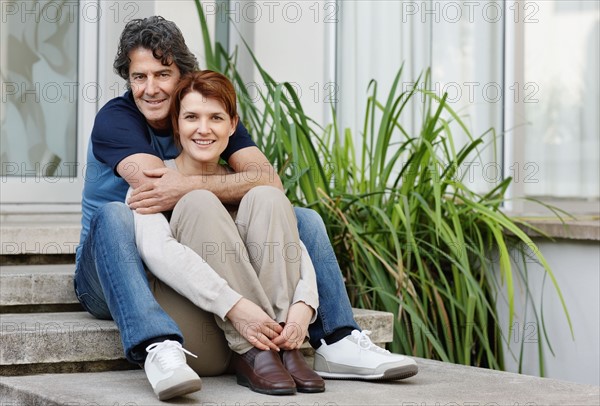 Happy couple sitting on steps together. Photo : momentimages