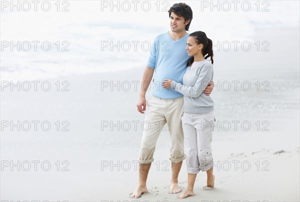 Couple walking barefoot on the beach. Photo : momentimages