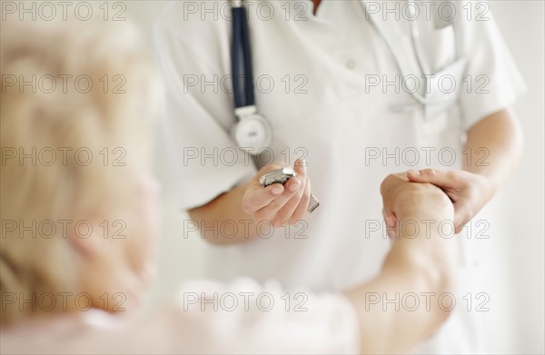 Nurse taking pulse of senior woman. Photo : momentimages