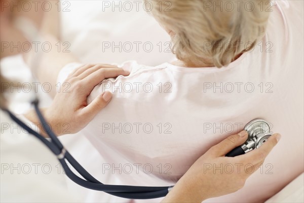 Nurse examining patient with a stethoscope. Photo : momentimages