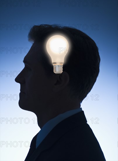 Light bulb in front of profile of a businessman.