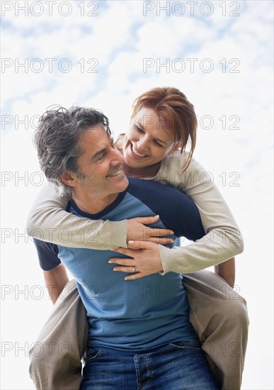 Man giving woman a piggy back ride. Photo : momentimages