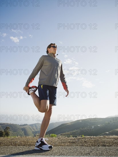 Runner stretching on the side of the road.