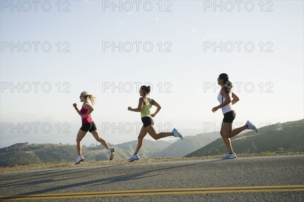 Runners training on side of a road.