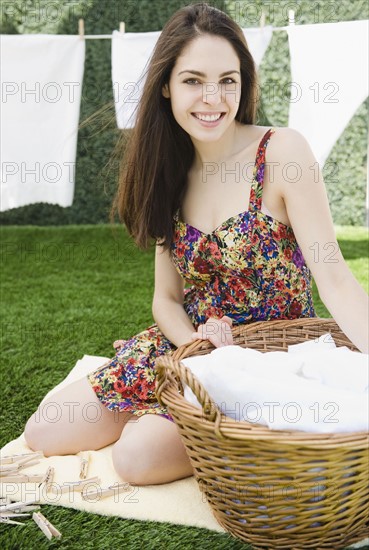 Young woman sitting beside a basket of laundry. Photo. Jamie Grill