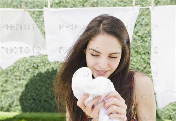 Young woman smelling clean laundry. Photo : Jamie Grill