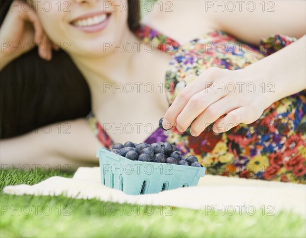 Young woman eating blueberries. Photo : Jamie Grill