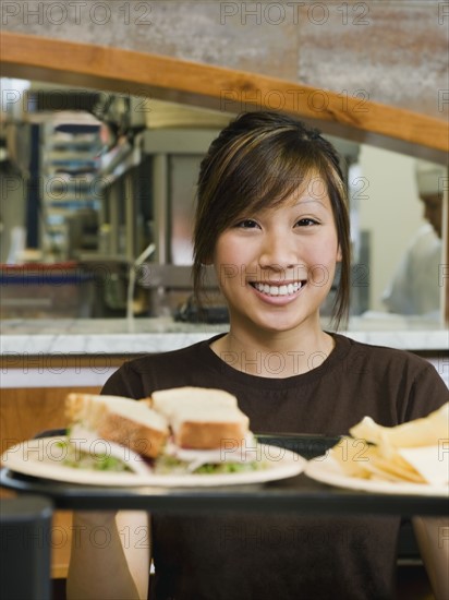 Woman holding tray of food.