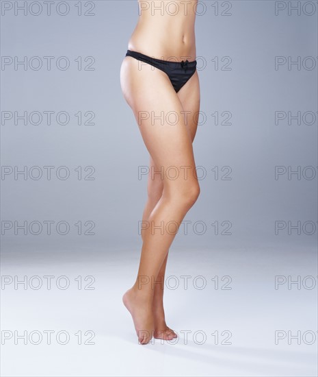 Legs and mid-section of woman wearing black panties. Photo : momentimages