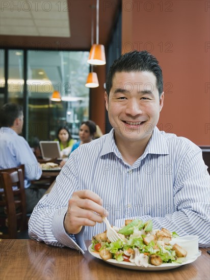 Man eating salad in restaurant.