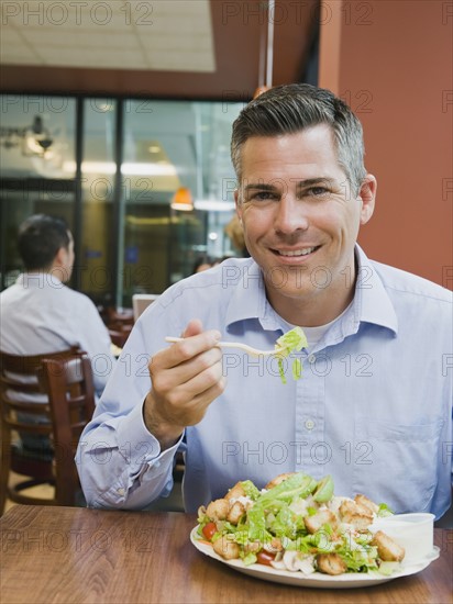 Man eating salad in restaurant.