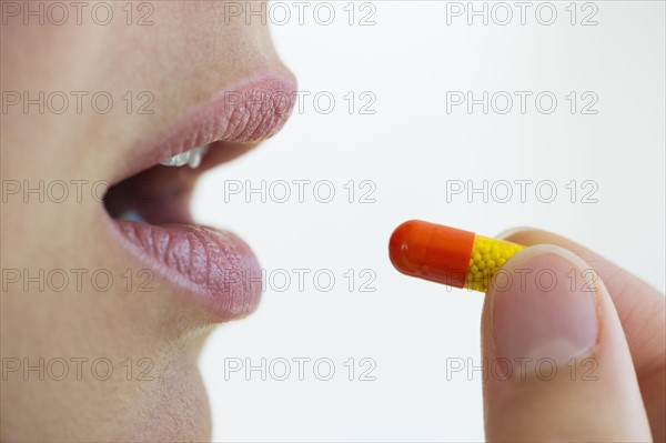 Woman putting capsule in her mouth.