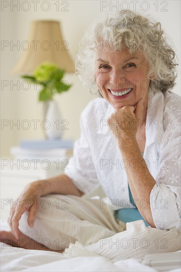 Portrait of a gray haired woman sitting on bed. Photo. Daniel Grill