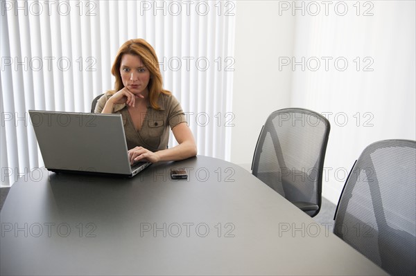 Businesswoman working on laptop in conference room.