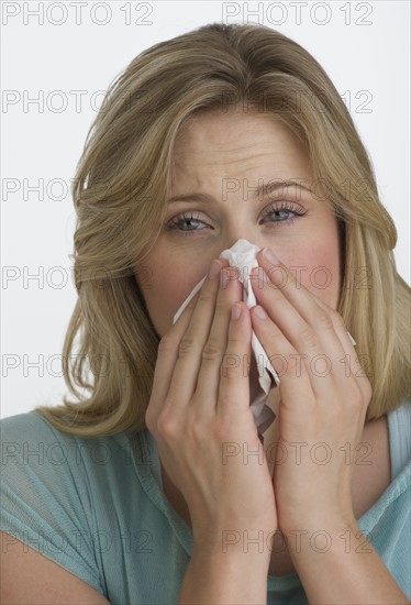 Blond woman blowing her nose.