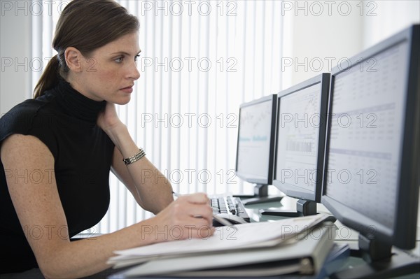 Woman in office working at desk with computers.