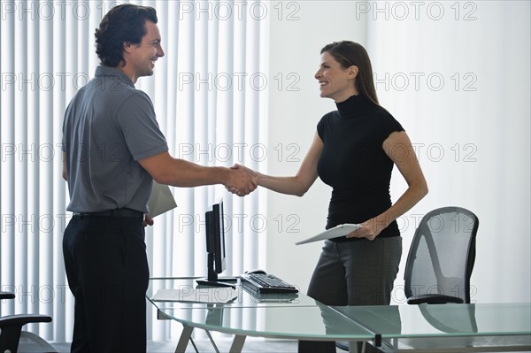 Man and woman in office shaking hands.